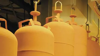 Freshly painted yellow LPG cylinders hanging on hooks