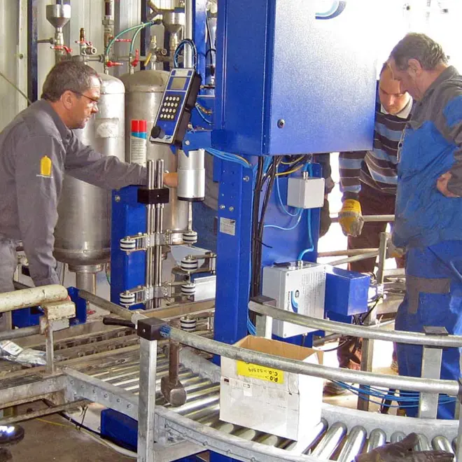 A picture of three men overlooking a filling machine
