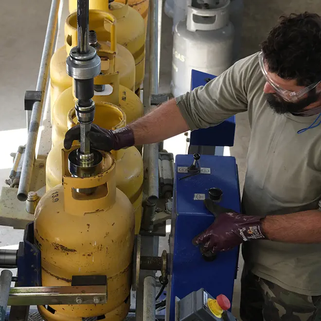 Image of a man handling yellow LPG cylinders on a chain conveyor line