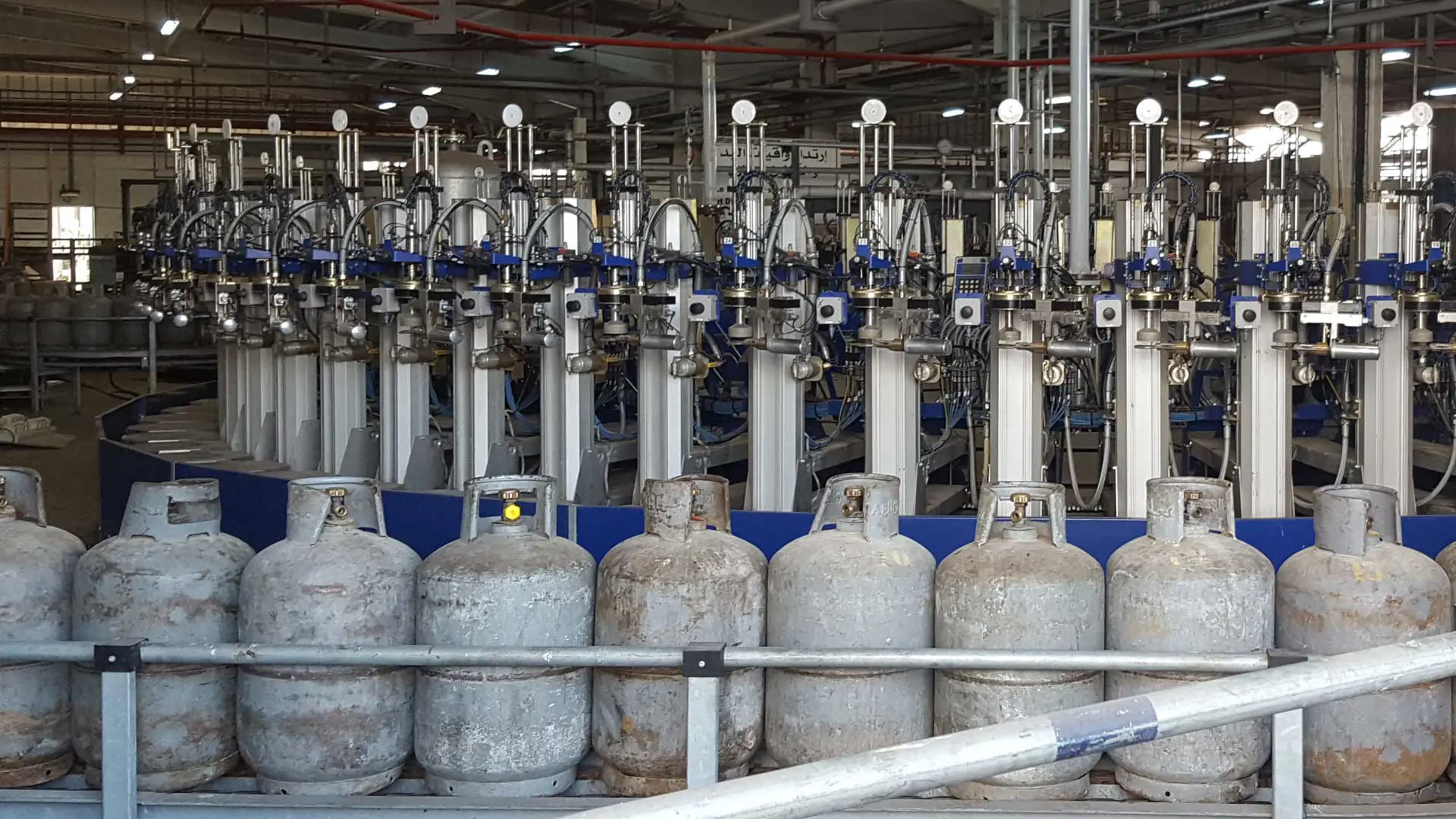 An image of cylinders on conveyer belt in front of filling machines