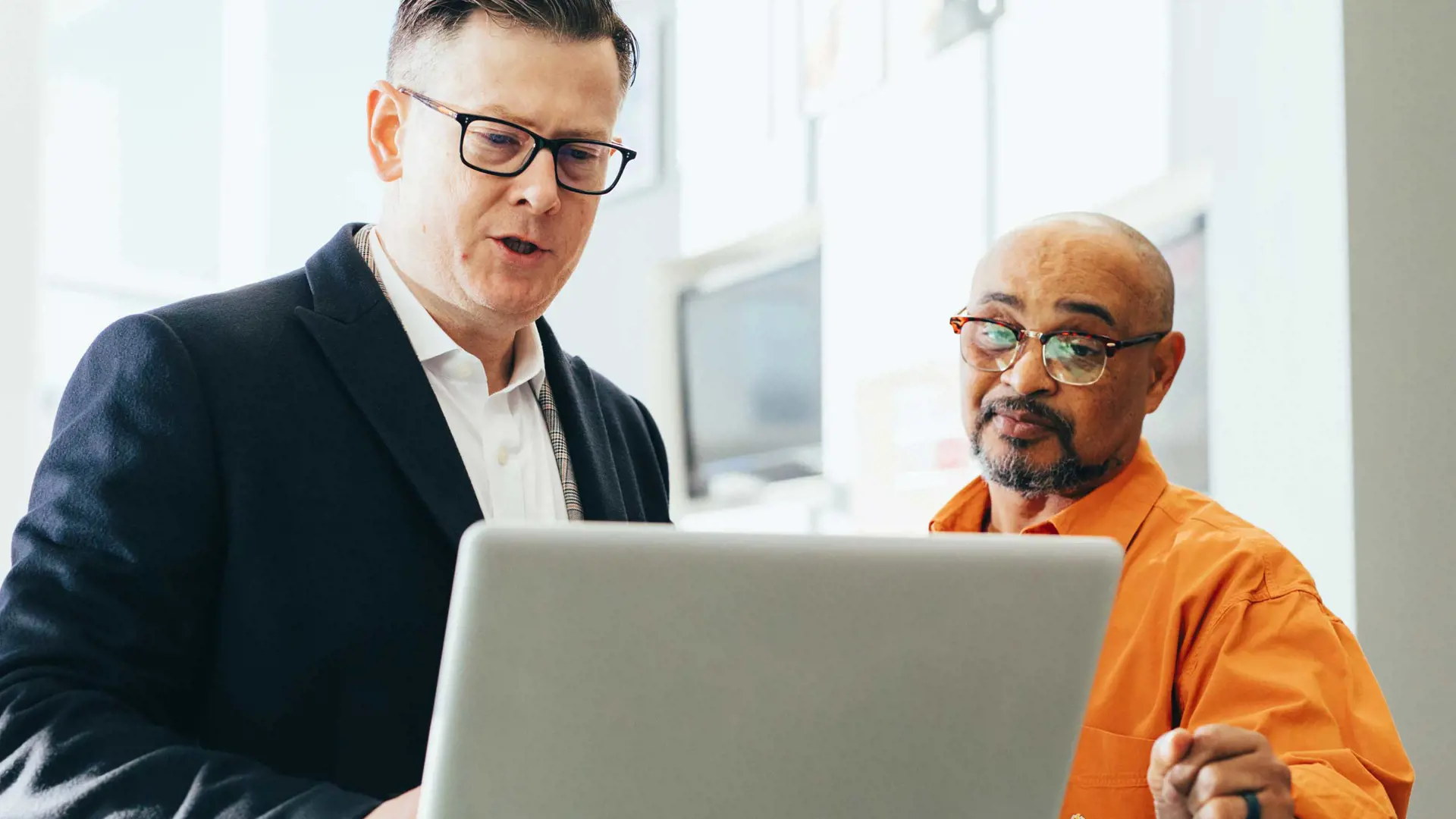 image of two men talking infront of a computer