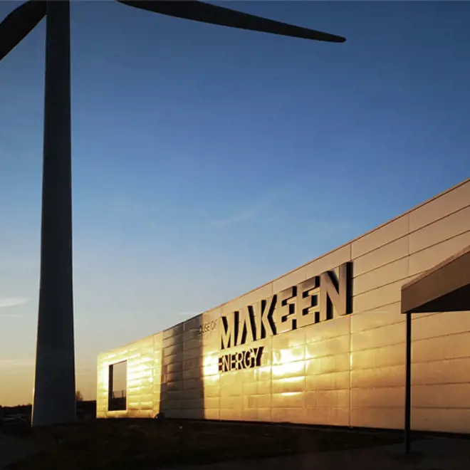 image of a building and a wind turbine in sunset text on the building saying House of MAKEEN Energy