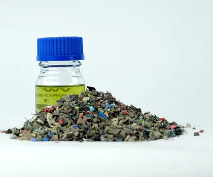 image of a glas with oil and a pile of shredded old plastic waste