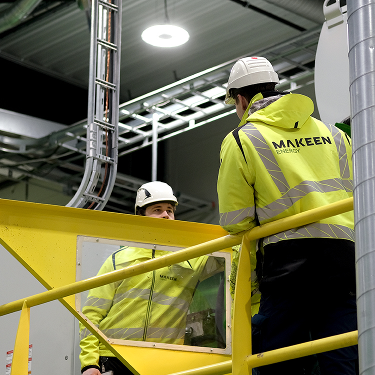 two MAKEEN Energy employees standing next to a machine