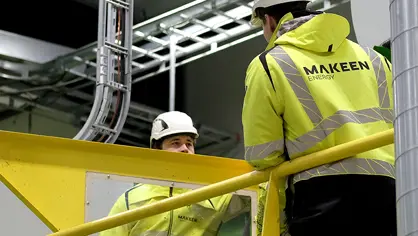 two MAKEEN Energy employees standing next to a machine