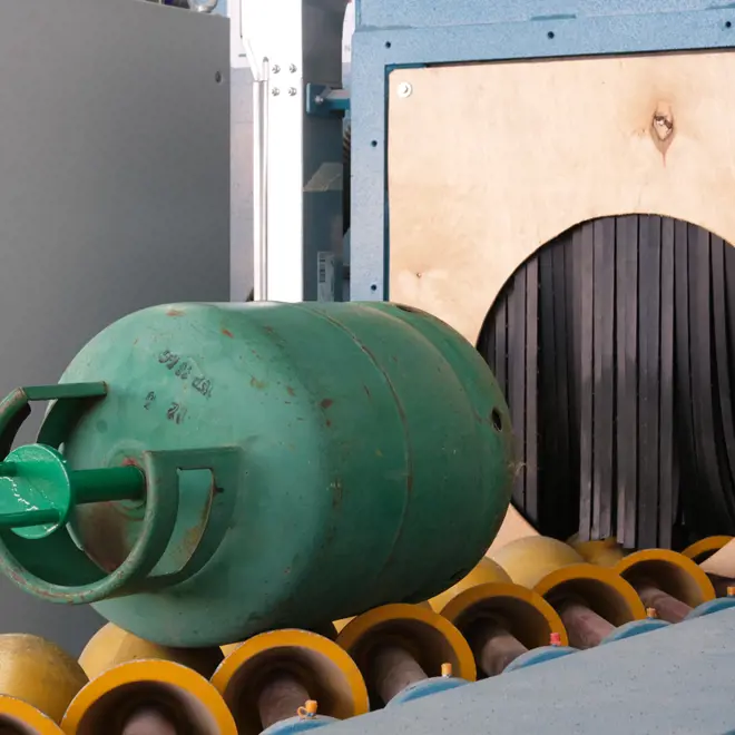 image of a green LPG cylinder laying on a track moving it to a washing machine