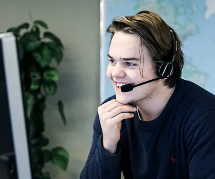 image of a smiling man at desk with headphones on customer support