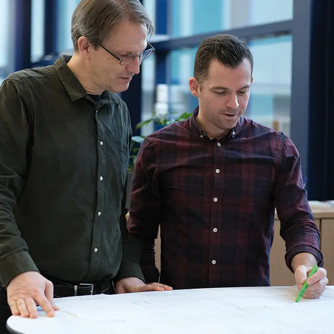 two engineerings talking and looking at a technical drawing