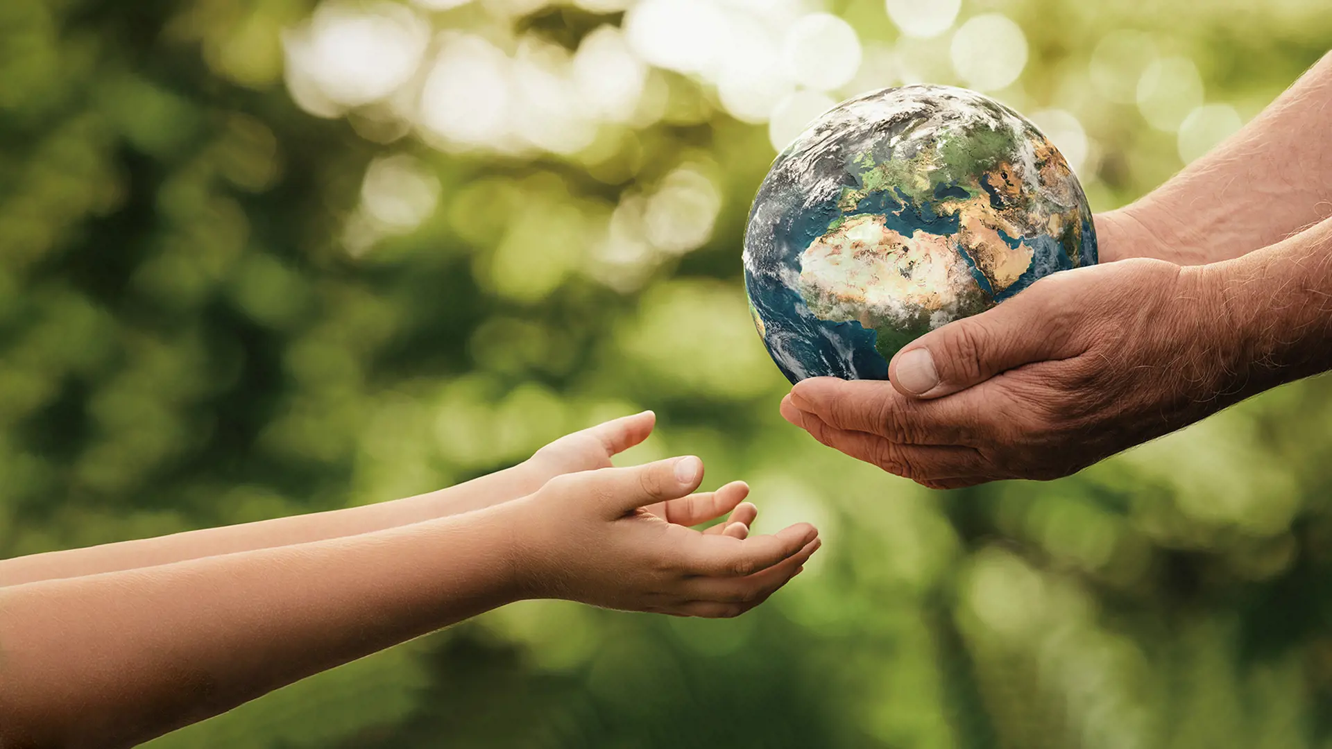 a child's hands reaching for a globe held by a grown man's hands