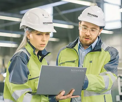 image of a man and woman in yellow jackets with white helmets holding a computer and talking