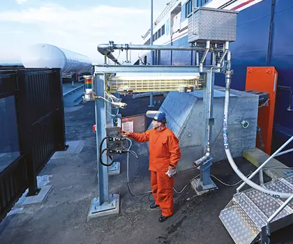 Male in orange cloth and with blue helmet is preparing to bunker a ferry with LNG