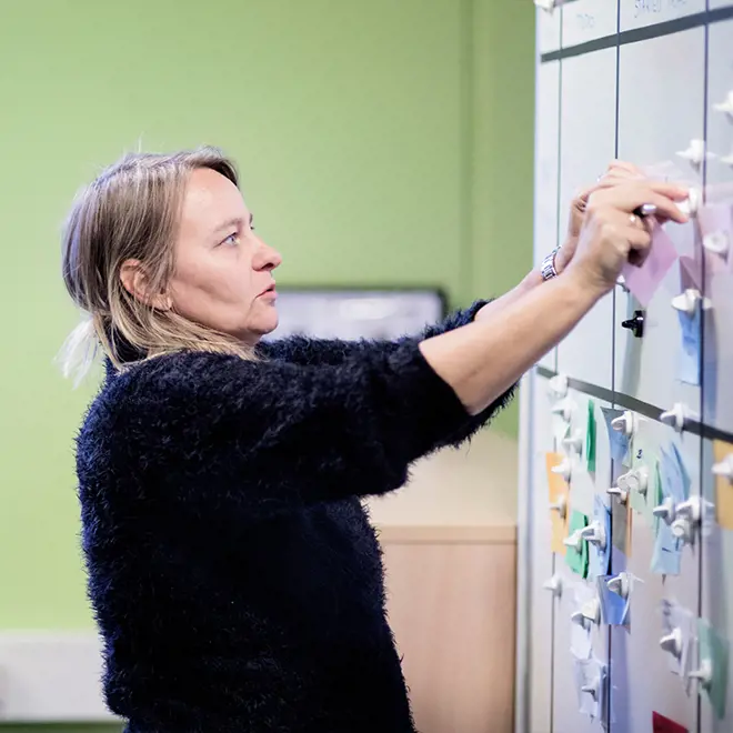 a woman rearranging items post-its on a whiteboard