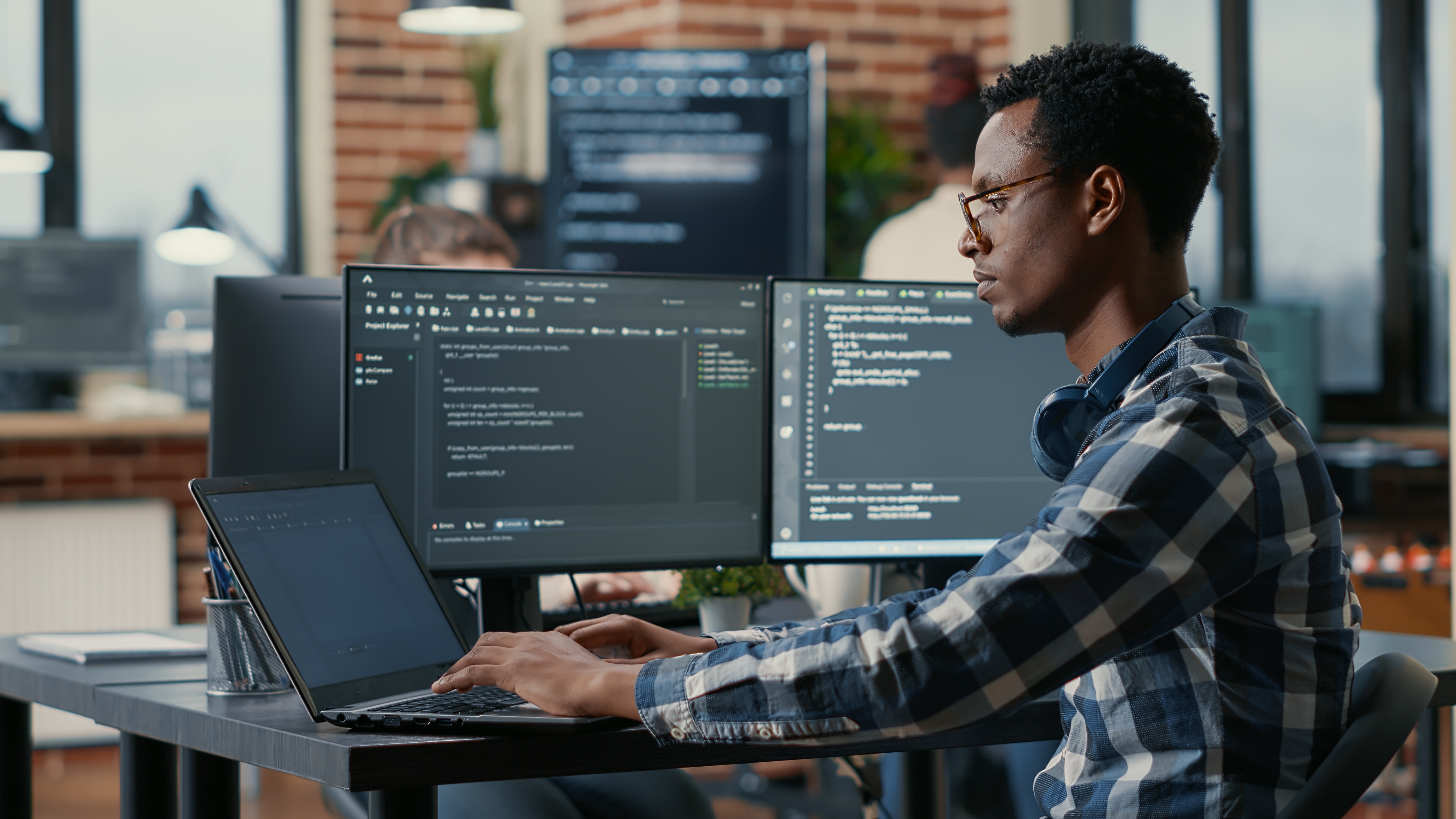 Man in checkered shirt writing code on a computer