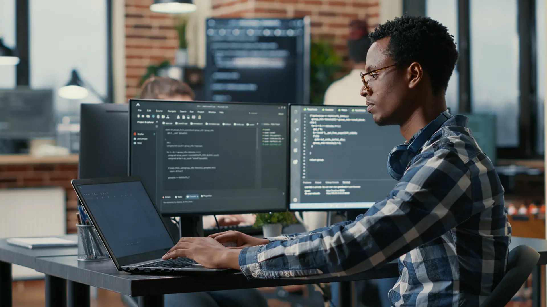 Man in checkered shirt writing code on a computer