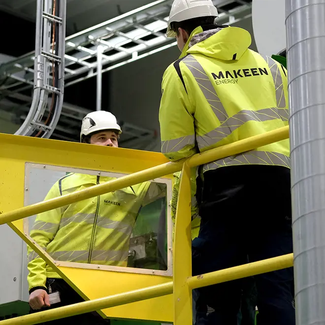 two MAKEEN Energy employees standing next to a machine