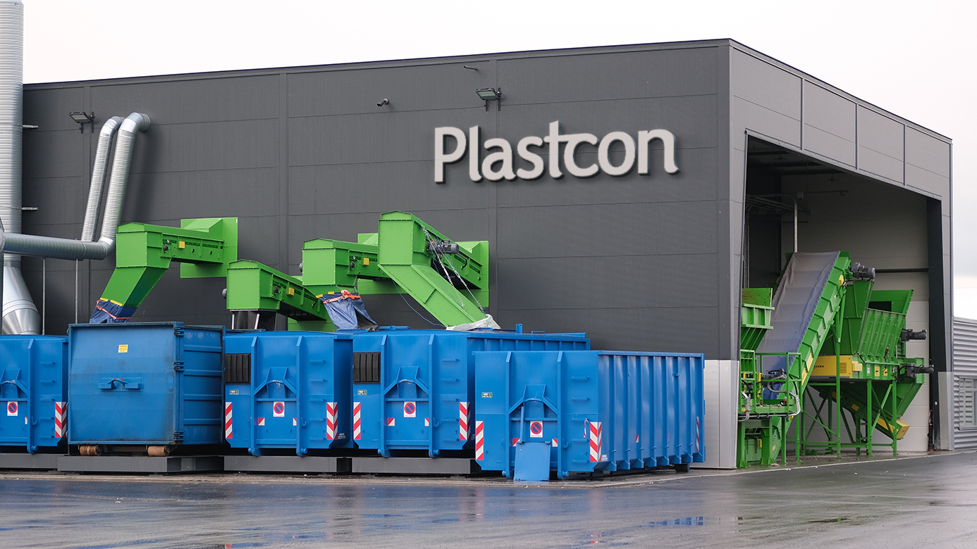 image of a plastic waste conversion plant with blue containers in front with a logo on the building saying Plastcon