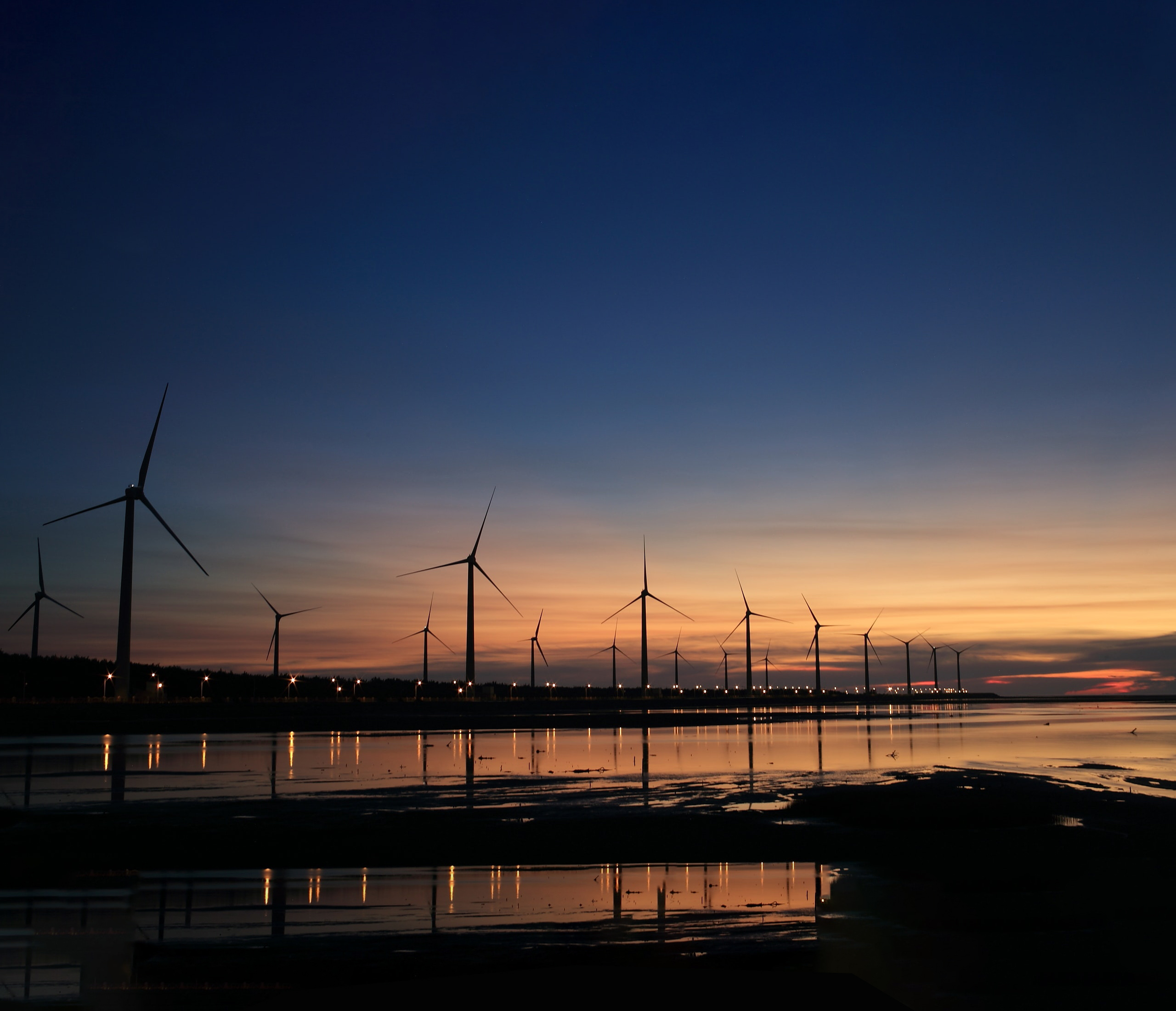 Coastal wind turbine farm at sunset