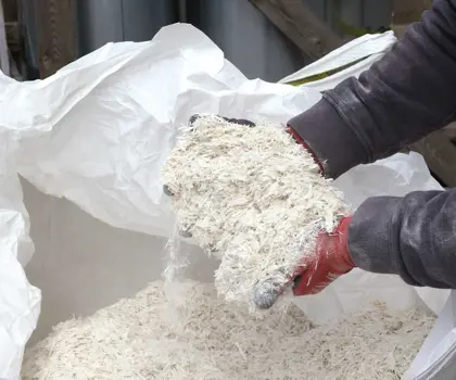 Shredded glass fibre being held by an unseen person